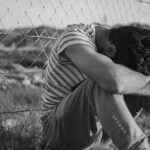 man in black and white stripe t-shirt leaning on chain link fence
